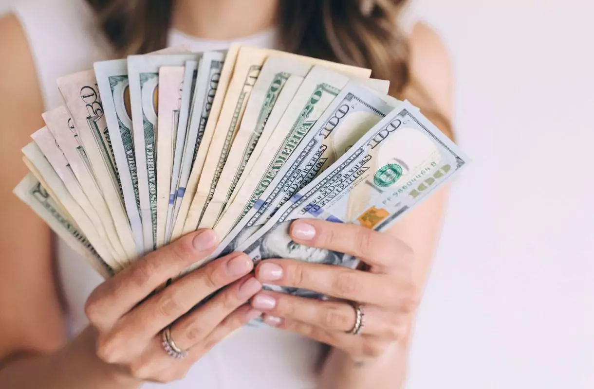 Woman holding dollar bills with both hands.