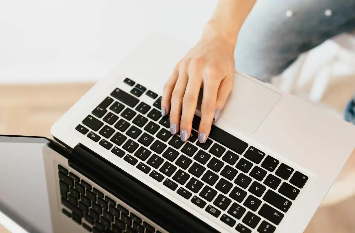 Close-up of a woman's hand, working on a laptop.