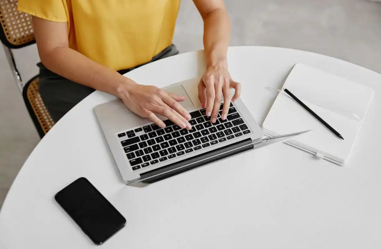 Rank IQ Review 2024. Woman wearing a yellow shirt, typing on a laptop.